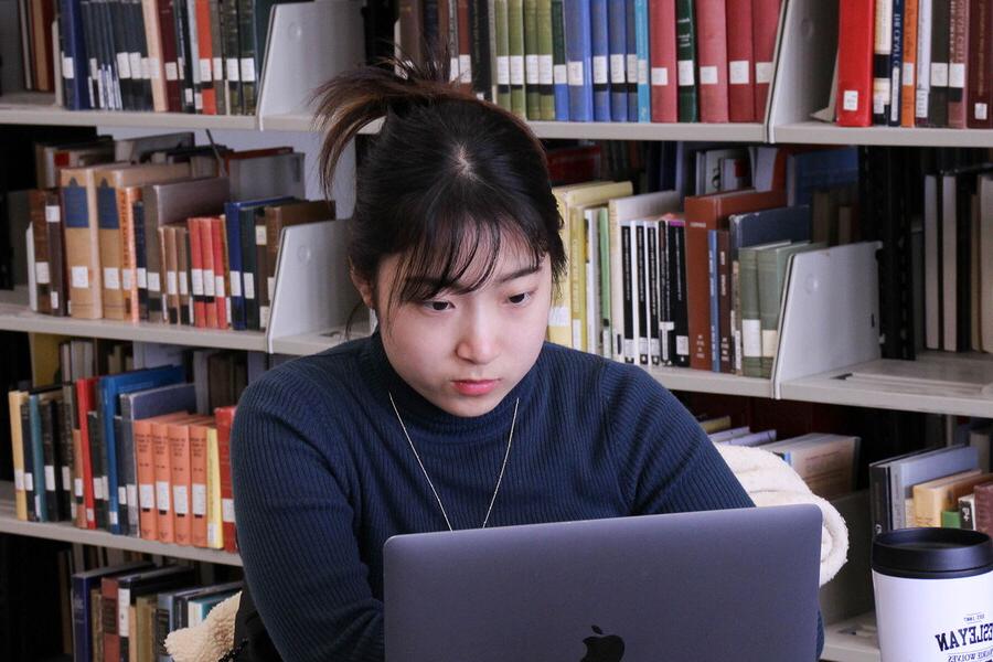 年轻女子在图书馆用笔记本电脑.